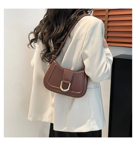 Deep brown matte leather crescent bag with golden U-shaped buckle on a model shoulder