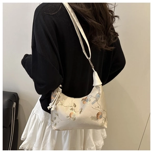 Detail of floral and bird print on beige satin shoulder bag with a crossbody strap