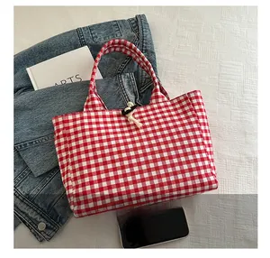 Detail showing the red gingham pattern tote bag with horn button closure and canvas texture