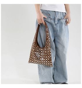 Detail of brown hobo bag featuring silver metal rivets and glossy patent leather finish