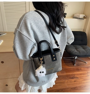 Détail du sac seau mat foncé avec poignée en PU noir et breloque monstre en peluche