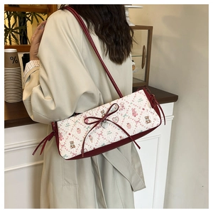 Detail of a chic shoulder bag featuring cute bear prints and a red bow metal pendant