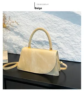 Close-up of beige crossbody bag with marble texture, round handle, and gold hardware