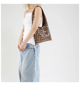 Close-up of brown bucket bag with silver studs and vintage finish on model's shoulder
