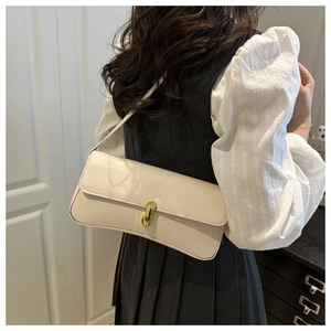 Detail of minimalist beige leather underarm bag with gold metal buckle on female model