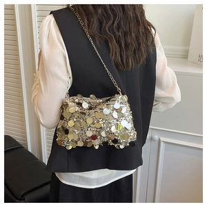 Detail of a chic gold sequin crossbody bag with a metal chain strap on a model