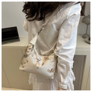 Detail of a chic cream handbag with vintage floral prints and beaded charm on the shoulder strap