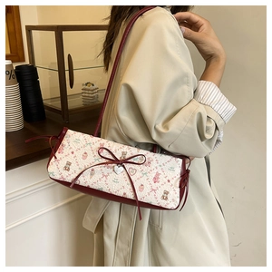 Detail view of contrast underarm bag featuring bear prints, red leather, and heart pendant