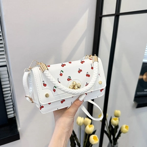 White PU leather handbag with cherry print and braided handle shown in a home setting