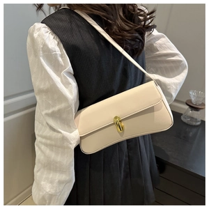 Close-up of cream rectangular shoulder bag with golden oval twist lock detail on model