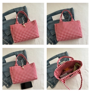 Detail of red checkered canvas tote bag with drawstring closure and large interior capacity