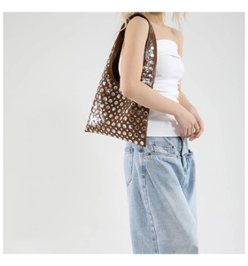 Detailed side view of brown leather shoulder bag with silver rivet stud decorations