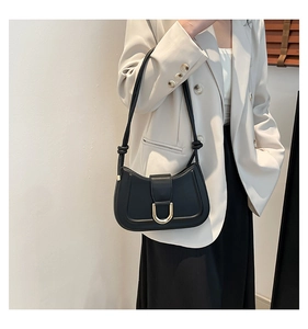 Close-up of a black leather shoulder bag with gold metal buckle and knotted handle detail