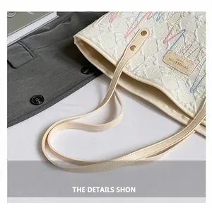 Close-up of the comfortable cream-colored handles of an embroidered canvas tote bag