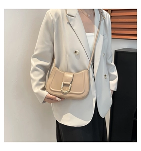 Model wearing a chic beige shoulder bag with a gold D-ring buckle and adjustable strap