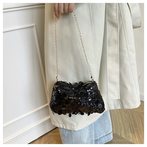 Detail of a chic black sequin crossbody bag with a slim gold chain and glossy finish