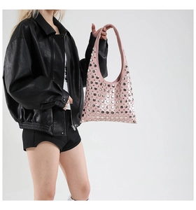 Detailed view of pink leather tote bag with silver studs worn by a model in black