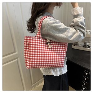 Detail of red checkered canvas tote bag with a wooden toggle button closure detail