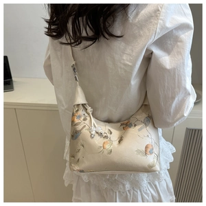 Detail of floral embroidery and bead tassel on a beige satin shoulder bag