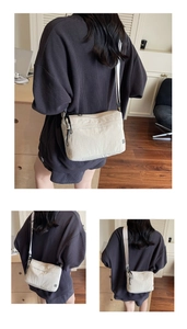 Dettaglio di una borsa a tracolla in nylon bianco crema con tessuto a trama e logo nero