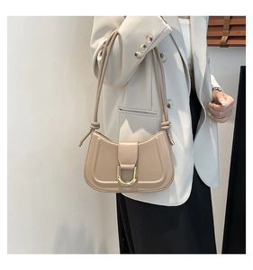 Detail of minimalist beige leather half-moon shoulder bag with golden D-ring magnetic clasp