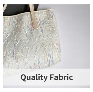 Close-up of embroidered canvas tote bag showing colorful wavy stitching and texture
