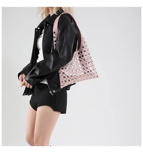 Close-up of pink faux leather bucket bag featuring silver metal rivets and wide shoulder strap