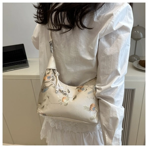 Detail showing elegant flower and bird embroidery on a cream satin crescent bag
