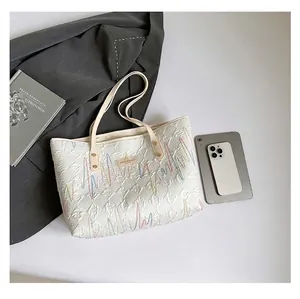 Detailed view of white embroidered canvas tote bag with smartphone for size comparison