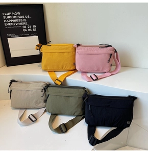 Dettaglio ravvicinato di borse messenger in nylon colorato su supporti geometrici