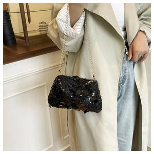 Detail of black sequined crossbody bag with gold chain strap on a trench coat model