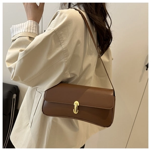 Detail of a brown vintage leather shoulder bag featuring a golden oval twist-lock closure