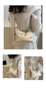 Detail of embroidered floral bird patterns on a cream hobo bag with bead tassels