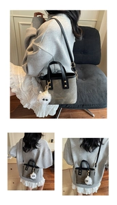 Detail view of the gray felt handbag with gold text and a white plush toy charm accessory