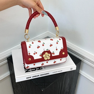 Stylish white crossbody bag with red cherry print and golden petal lock on top handle