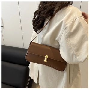 Close-up of vintage brown leather baguette bag with a sleek gold oval buckle clasp