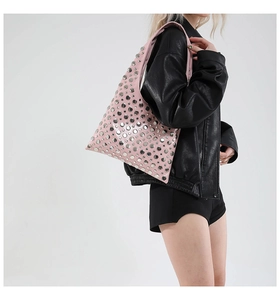 Detailed view of pink hobo bag featuring silver rivets worn by a model in a leather jacket