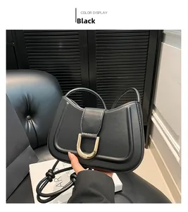Detail of black matte leather handbag featuring a gold U-shaped buckle and knot handles