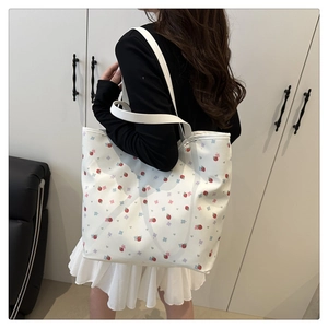 Detail of floral strawberry print tote bag shown being worn on the shoulder