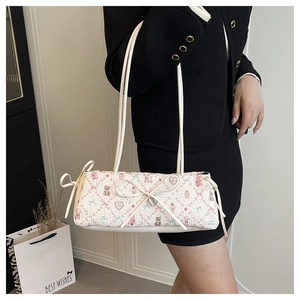 Detail of floral bear print shoulder bag with bow and heart charm on a model