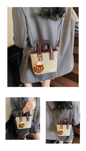 Detail of beige canvas and brown leather crossbody bag with a plush lion keychain