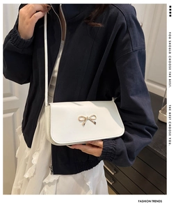 Détail du sac à bandoulière blanc orné d'une boucle décorative en métal doré en nœud