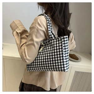 Detail of black and white checkered canvas tote bag with decorative woven drawstrings