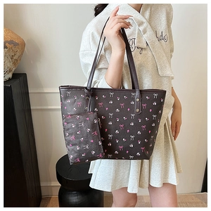 Detail of dark brown tote bag set featuring pink bow prints and matching inner pouch
