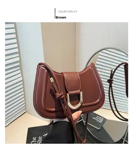 Detail view of brown vintage shoulder bag with golden horseshoe buckle and knot strap