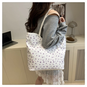 Detail of white tote bag with purple floral pattern and bow prints in a lifestyle setting