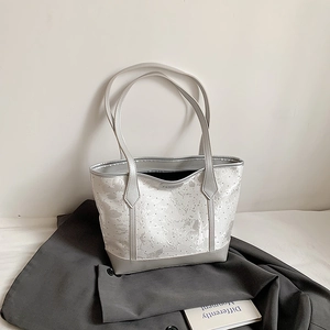 Silver tote bag with butterfly patterns and double straps on a grey blazer background