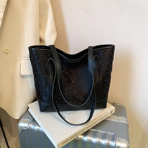 Floral print black tote bag with leather straps displayed on luggage for business travel