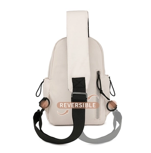 Detail view showing the reversible shoulder strap design on a cream canvas chest bag
