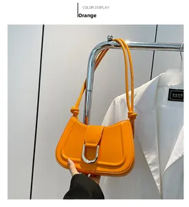 Detail of an orange glossy leather shoulder bag featuring a silver U-shaped metal buckle